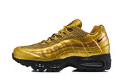 Side profile of a gold-tone Nike Air Max 95 TT sneaker with layered panels and visible cushioning windows.