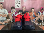 Front view of a pair of navy basketball sneakers with bright red laces, perforated toe panels, and red-and-black tongue logos.