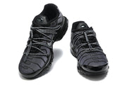 Front view of a pair of black and grey Nike Air Max Plus sneakers.