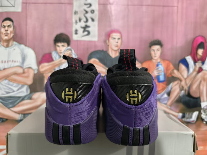 Rear view of purple basketball sneakers showing black heel panels, red-stitched pull tabs, and dark-and-gold heel emblems.