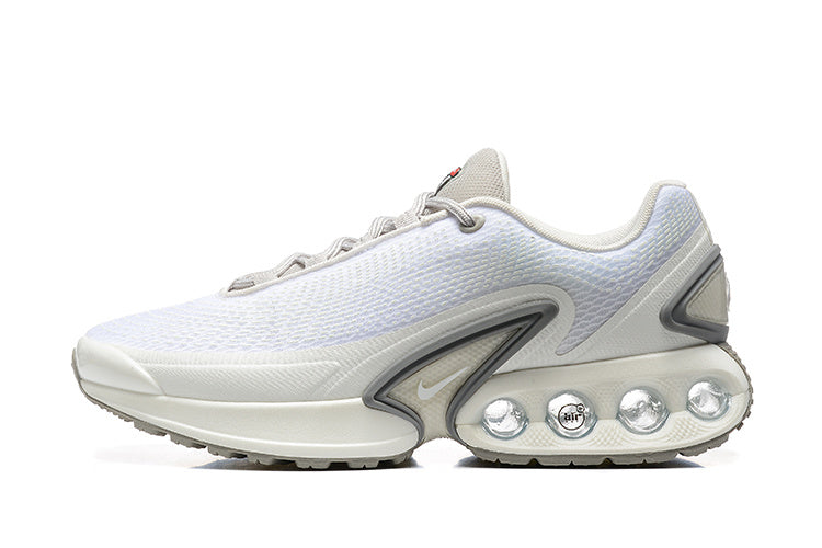 Side view of white and grey Nike Air Max DN sneakers with visible circular sole elements.