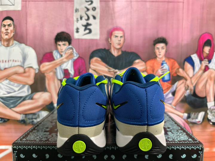Rear view of blue Nike sneakers with white heel sections and neon green logo accents