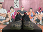 Front view showing black laces, camouflage toe boxes, red tongue logos, and olive outsoles.