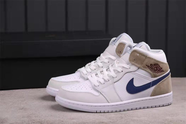 Side profile of the white, dark blue, and tan Jordan Air Jordan 1 Mid sneakers.