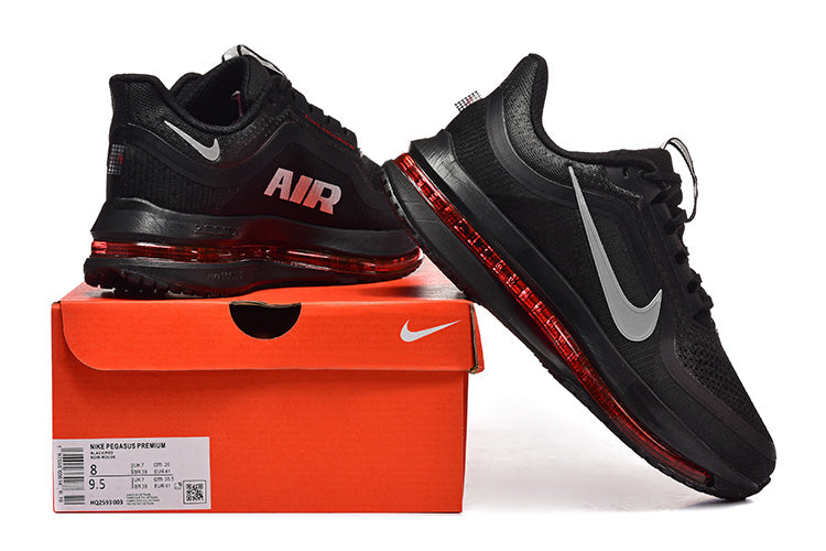 Black Nike Pegasus Premium shoes with gray Swoosh details and red sole accents displayed with an orange shoe box.