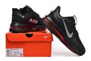 Black Nike Pegasus Premium shoes with gray Swoosh details and red sole accents displayed with an orange shoe box.