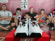 Front view of white Nike basketball sneakers with black and red tongue details, white laces and black toe accents.