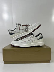 Stacked view of the two white low-top sneakers with patterned uppers and dark red outsoles.