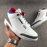 Handheld three-quarter view showing the white high-top sneaker and its patterned toe and heel details.