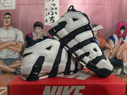 Angled view of white and dark navy Nike basketball shoes with oversized AIR lettering.
