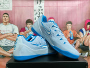 Angled side view showing the light blue upper, blue Nike Swoosh, perforated side panels, blue laces, and textured outsole.