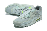 Angled top view of gray Nike Air Max 90 QS sneakers with lime details.