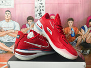 Red Nike LeBron basketball shoes shown from the side, with white Swoosh details, navy accents, and a speckled midsole.