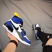 Angled side view highlighting the black Swoosh-style detail, elephant-print panel, strap, and layered sole.