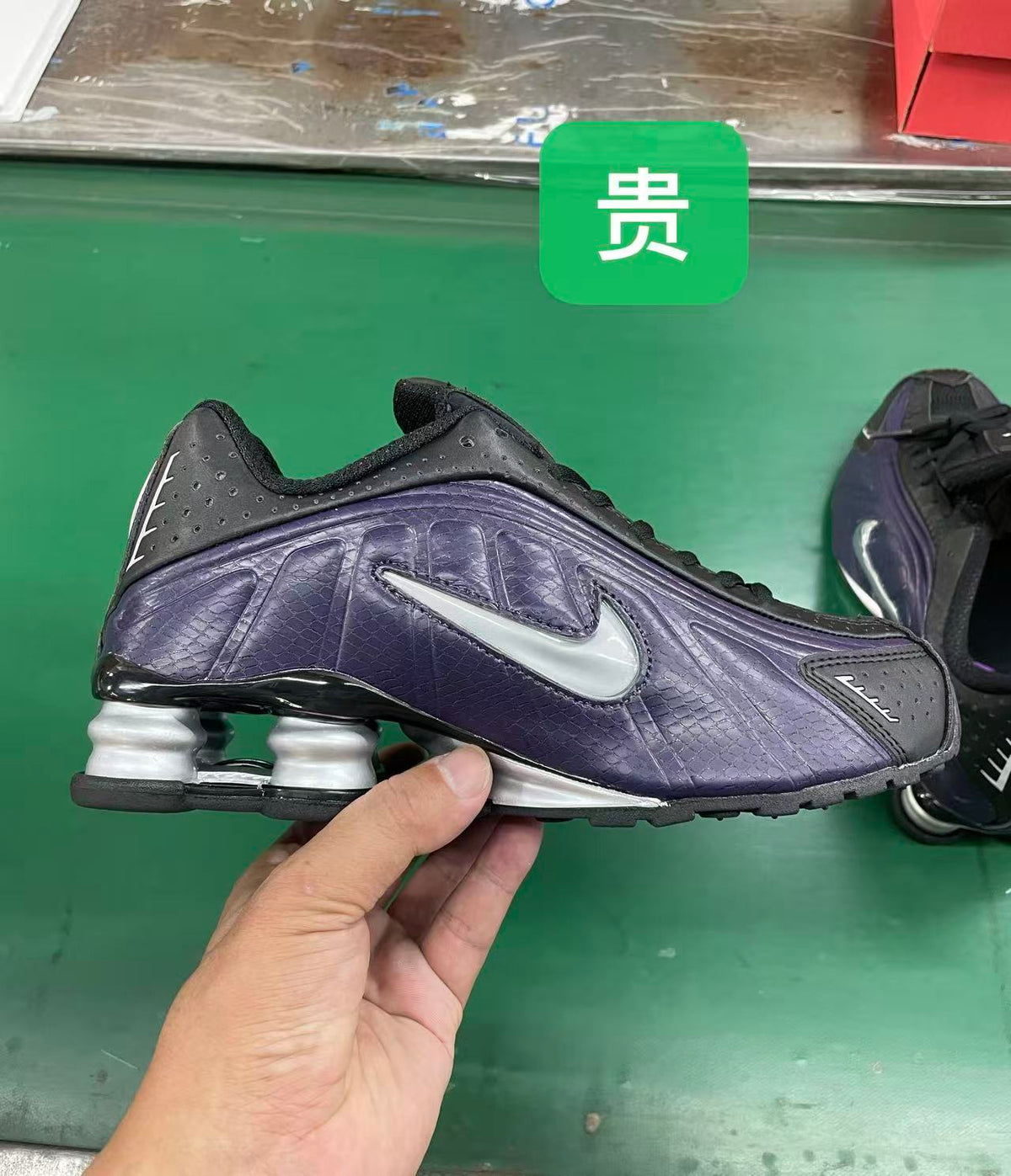 Side view of a black and purple Nike sneaker with a silver-colored Swoosh and heel columns.