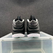 Rear view of a pair of black Nike sneakers with white outsole sections, heel Swoosh details and Foamposite tongue branding.