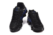 Front view of a pair of black Nike Shox TL sneakers with blue details.