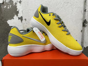 Angled view of yellow Nike sneakers with black and silver Swooshes and ridged white soles