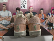 Rear view of the pair showing perforated pink heel panels, silver detailing, green Nike branding, and cream midsoles.