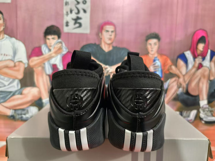 Rear view of black and red sneakers showing pull tabs, layered heel panels, contrasting heel accents, and a patterned background.