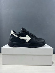 Single side profile of the black and white sneaker showing its low-top silhouette, white arrow detail, and textured outsole.