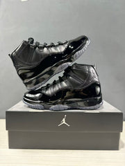 Two black high-top sneakers arranged on a Jordan shoebox, showing the side profile and translucent outsole.