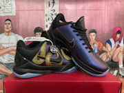 Angled view of two Nike basketball sneakers showing gold side accents, purple panels, black collars, and translucent outsoles.