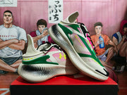 Angled view of the pair highlighting the green side structure, pink panels, Under Armour logos and patterned midsoles.