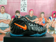 Side profile of a black Nike Foamposite sneaker showing orange side branding, sculpted panels and a blue outsole.