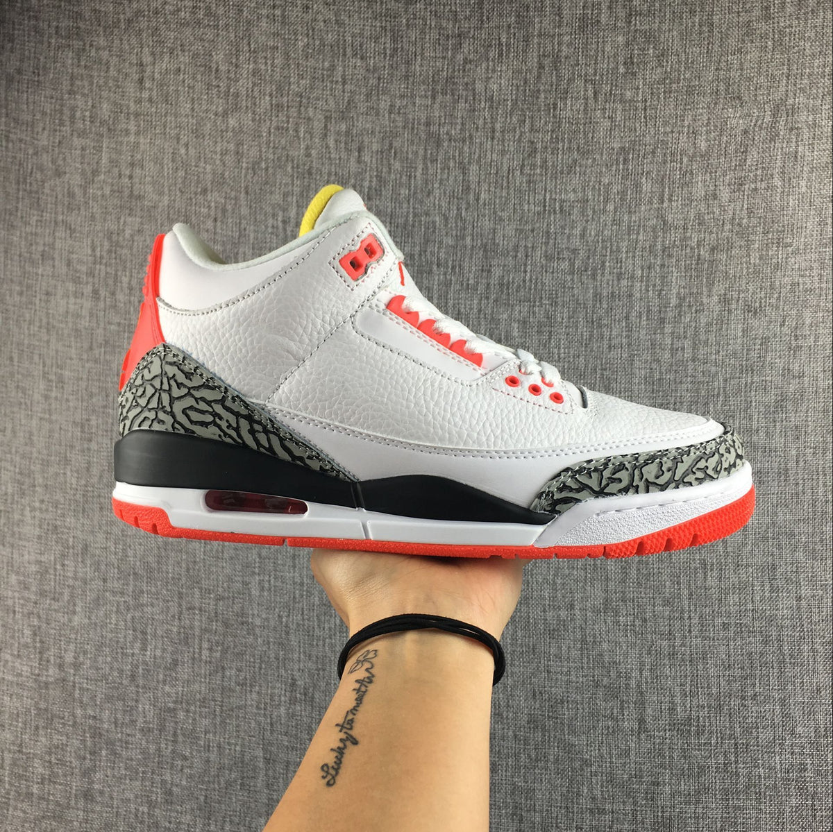 Side view of a white Jordan 3 sneaker with elephant-print overlays and red accents.