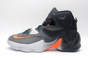 Side profile of a black and white Nike high-top basketball shoe with orange detailing and a padded collar.