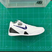 Side view of a white low-top basketball shoe with a purple Swoosh, black panels, and speckled midsole
