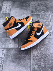 Pair of high-top sneakers arranged on a tiled surface, showing orange-and-black uppers and white midsoles.