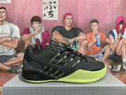 Side view of a black Nike basketball shoe with green accents and a volt-green outsole