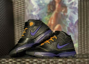Pair of sneakers displayed together, highlighting the black upper, purple accents, and yellow lace details.