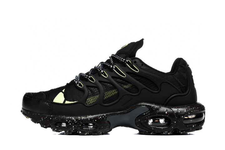 Side view of black Nike Air Max Plus Utility sneakers with neon green accents, patterned laces, and a speckled sole.