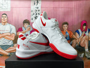 Angled view of white Nike basketball shoes showing red Swoosh logos and red outsole accents.