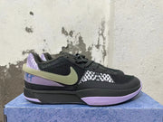 Side view of black Nike basketball shoe with lavender trim, patterned panel, and olive-toned Swoosh
