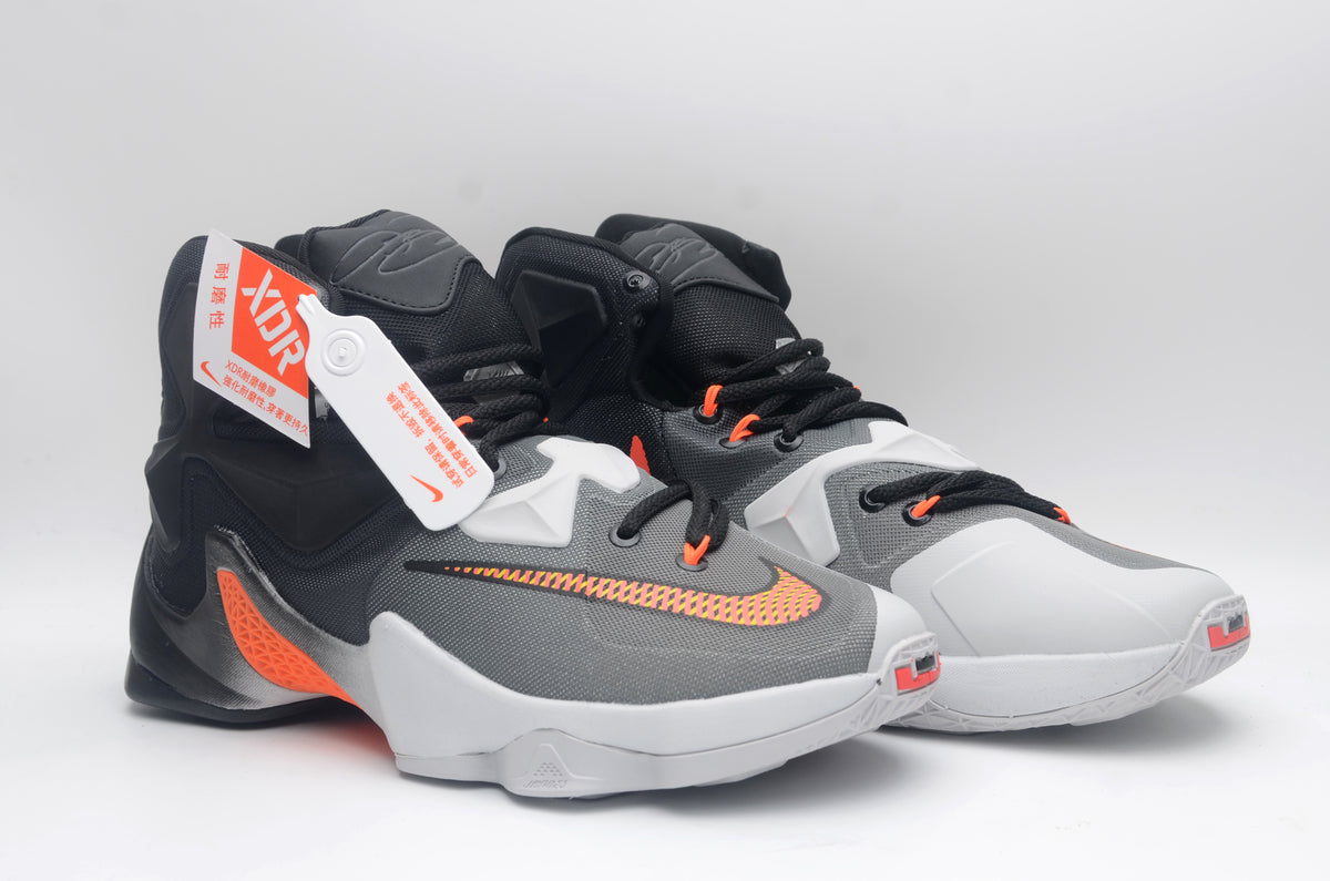 Pair of black, white, and orange Nike high-top basketball shoes shown from a front three-quarter angle.