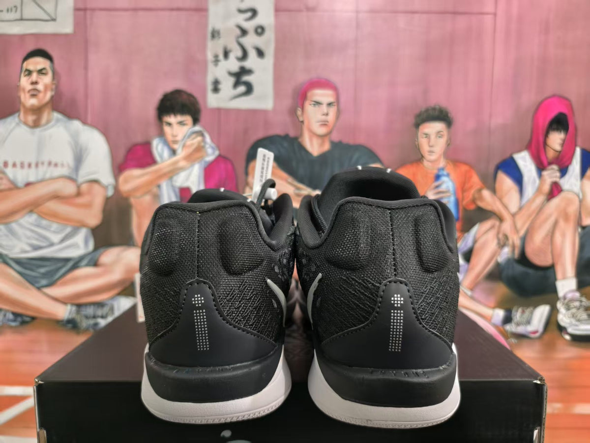 Rear view of black basketball sneakers with white midsoles and padded collars on a shoebox.