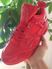 Close-up of a glossy red high-top sneaker showing its tongue, laces, mesh panel, and side wing.