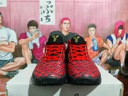 Front view of black and red basketball sneakers with bright red laces, patterned uppers, and gold tongue logos.