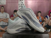 Angled side view showing the layered upper, translucent side details, and sculpted sole of the white and silver sneakers.