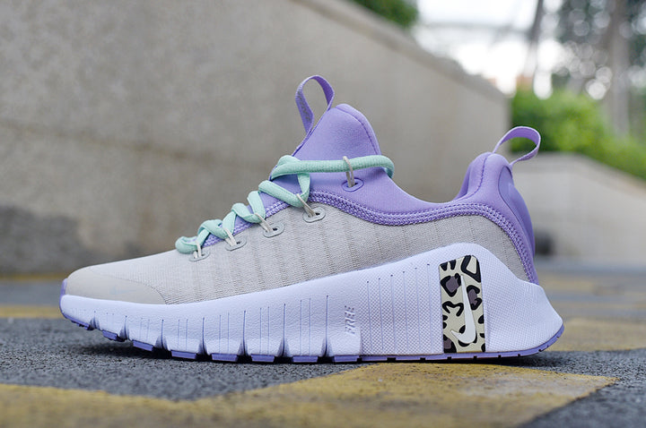 Low-top Nike sneaker in light gray-white, lavender and mint green, shown from the side with a patterned accent panel.