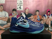 Side view of a navy Nike Kobe basketball shoe with aqua side logo and outsole