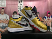 Pair of gold and white basketball shoes shown from the side, with burgundy laces and Kobe signature details