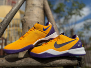 Angled side view of gold Kobe 8 shoes with purple accents