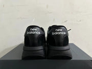 Rear view of black New Balance U370 sneakers with white heel branding.