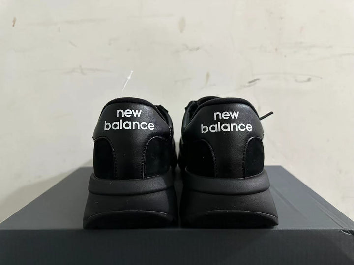 Rear view of black New Balance U370 sneakers with white heel branding.