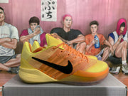 Side profile of one orange and yellow sneaker with a black Swoosh and translucent outsole.